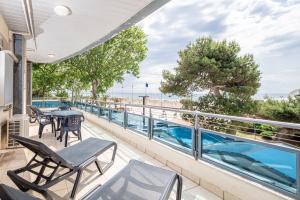 a balcony with tables and chairs and a view of the beach at Monaco Apartments in Lignano Sabbiadoro
