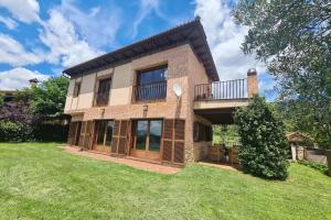 a large brick house with a balcony on a lawn at Villa Juan in La Adrada