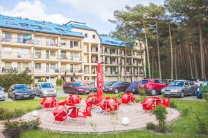 eine Gruppe roter Tische und Stühle vor einem Hotel in der Unterkunft Blue Mare Hebe Apartament in Łukęcin