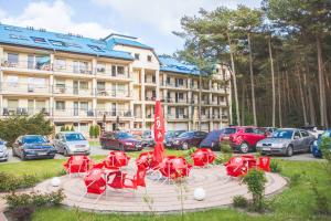 a group of red tables and chairs in front of a hotel at Blue Mare Hebe Apartament in Łukęcin