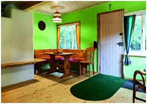 uma sala de jantar com paredes verdes e uma mesa de madeira em Elfenhütte Ferienhaus Eifel em Rott