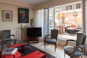 ein Wohnzimmer mit einem Flachbild-TV und Stühlen in der Unterkunft Bright cocoon with large terrace in Paris