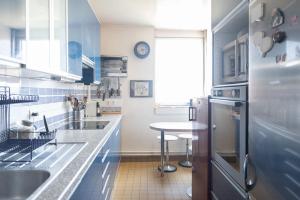 uma cozinha com armários azuis e uma mesa em Bright cocoon with large terrace em Paris