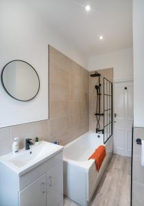 a bathroom with a tub and a sink and a mirror at `isimi Burnley [ Modern 3 Bedroom House] in Burnley