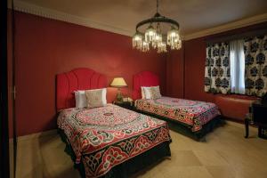 een rode slaapkamer met 2 bedden en een kroonluchter bij Le Riad Hotel de Charme in Caïro