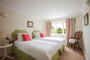 Duas camas num pequeno quarto com uma janela em High Meadows em Saint Mawes