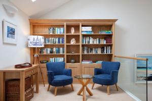 una oficina con 2 sillas azules, escritorio y estanterías de libros en High Meadows, en Saint Mawes