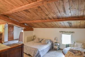 sypialnia z łóżkiem i drewnianym sufitem w obiekcie Chambres d'hôtes "Le Colombier" w mieście Venasque