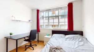 Schlafzimmer mit einem Bett, einem Schreibtisch und einem Fenster in der Unterkunft Superb Studio Apartment in London