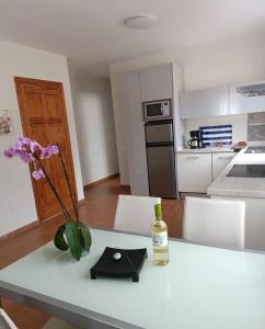 a kitchen with a table with a bottle of wine and flowers at Mogan Sol in Puerto de Mogán