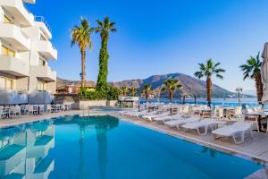 einen Hotelpool mit Stühlen und Palmen in der Unterkunft MARBAS SELECT BEACH , Adult Only 14 Plus in Marmaris