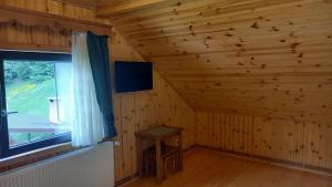 Cette chambre dispose d'une fenêtre dans une cabane en rondins. dans l'établissement Pensiunea agroturistică Casa Brădeana, à Albac