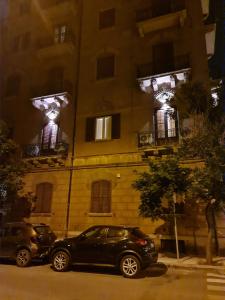 two cars parked in front of a building at night at Mama Tita Rooms and Breakfast in Palermo