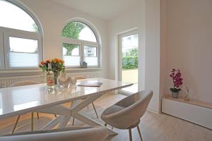 una sala da pranzo con tavolo e sedie e due finestre di Haus Sanke strandnah a Ahlbeck