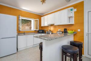 a kitchen with white cabinets and bar stools at Casa Penney in Denia