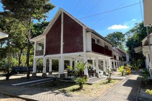 a house on a street with trees in the background at Capital O 92612 Penginapan D'alas Purwo & Beach in Banyuwangi