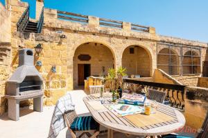 una mesa y sillas en un patio con horno de pizza en Matli Farmhouse, your stunning Gozo getaway., en Munxar