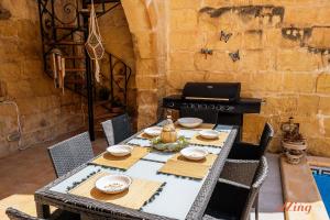una mesa de comedor con sillas y un ordenador portátil en la estufa en Matli Farmhouse, your stunning Gozo getaway., en Munxar