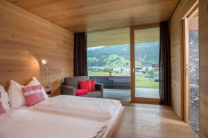 a bedroom with a bed and a couch and a window at Smaragdresort in Bramberg am Wildkogel