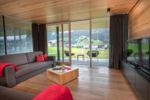 a living room with a couch and a tv at Smaragdresort in Bramberg am Wildkogel