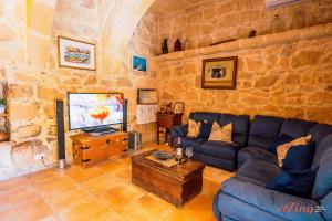 sala de estar con sofá azul y TV en Matli Farmhouse, your stunning Gozo getaway., en Munxar