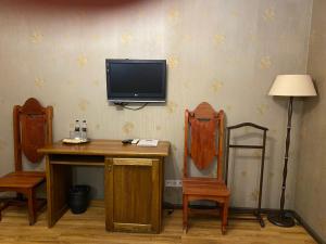 uma televisão numa parede com uma mesa e duas cadeiras em Hotel Fortetsya Hetmana em Hatne