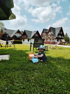 Un petit garçon assis dans l'herbe avec un camion à jouets dans l'établissement Gniewnik, à Białka Tatrzańska