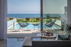 um pátio com 2 cadeiras, uma mesa e uma piscina em Crete Resort Sea Side Suites "Adults Only" by Checkin em Gouves