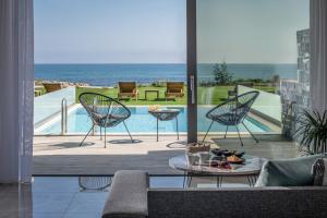 a patio with two chairs and a table and a pool at Ebenus Suites "Adults Only" by Checkin in Gouves