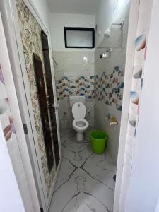 a bathroom with a toilet and a green bucket at Marigold Hotel in Siliguri