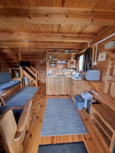 Apartamentowe domki drewniane COLORADO في كارفيا: غرفة معيشة مع أرضيات خشبية ومطبخ في كابينة خشب