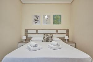 a bedroom with a large white bed with two towels at Apartagal-Océano V Barreiros in Barreiros +106 photos