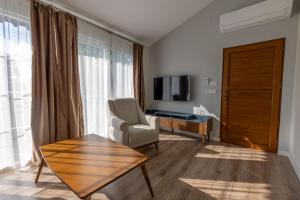 a living room with a television and a chair and a table at Caretta Caretta Pension in Cıralı
