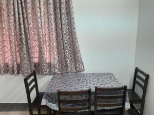 a dining room table with two chairs and a curtain at BareFootBay - Villa with Private Beach Access in Chennai