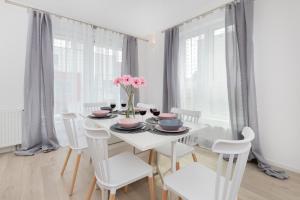 a white dining room with a white table and chairs at Garnizon Apartment for 6 Guests with Parking & Balcony by Renters in Gdańsk
