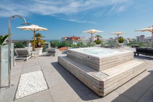 un patio con bañera de hidromasaje, sillas y sombrillas en Hotel Monaco, en Lignano Sabbiadoro