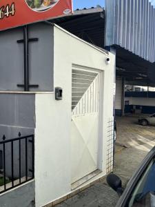 um edifício branco com uma porta ao lado em Quartos Delfim Moreira em Varginha