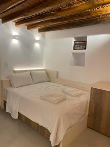 Una cama en una habitación blanca con dos toallas. en Cozy apartment Kostos en Kóstos
