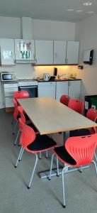 a kitchen with a wooden table and red chairs at Solborg Folkehøgskole Hostel in Stavanger