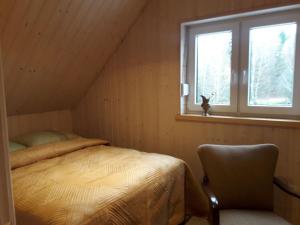 Potęgowo的住宿－OSTOJA PAWIE OKO，一间卧室设有一张床、一个窗口和一把椅子