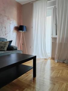 uma sala de estar com um sofá, uma mesa e uma janela em Apartman_Krstić_1 em Subotica