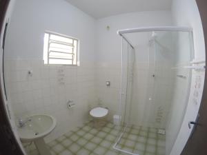 ein Bad mit einer Dusche, einem WC und einem Waschbecken in der Unterkunft Quartos Delfim Moreira in Varginha
