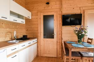 a kitchen with a table and a tv on the wall at słoneczny domek II in Kołczewo +11 photos