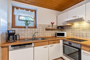 a kitchen with white cabinets and a sink at Haus Weber in Hölzberg