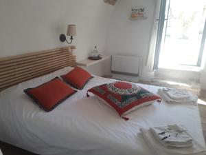 Orgnac-lʼAvenにあるUne Nuit au Village - chambre d'hôtes de charmeの白いベッド(赤い枕付)