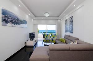 a living room with a couch and a tv at Gulf Palace Apartments in Limassol