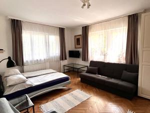 a living room with a couch and a bed and windows at Tisch Vendégház in Hajdúszoboszló