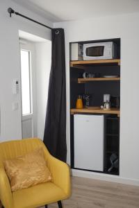 ein Wohnzimmer mit einem gelben Stuhl und einer Mikrowelle in der Unterkunft Riva Studio in Saint-Aignan