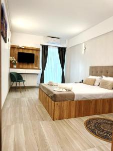 een slaapkamer met een groot bed en een televisie bij Victory Luxury Apartments in Eforie Nord