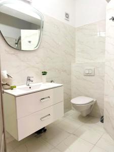 bagno con lavandino, servizi igienici e specchio di Victory Luxury Apartments a Eforie Nord
